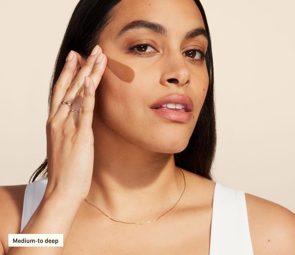 Woman applying SilkScreen to face (medium-to-deep)